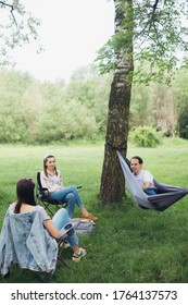 Social distancing. Small group of people enjoying conversation at picnic with social distance in summer park. Leisure activity together in new normal, gatherings following safety protocols