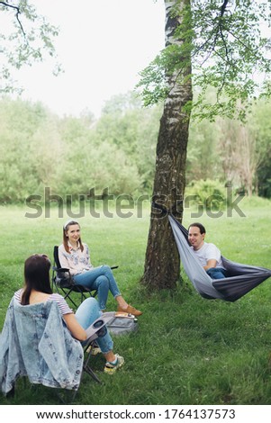 Social distancing. Small group of people enjoying conversation at picnic with social distance in summer park. Leisure activity together in new normal, gatherings following safety protocols