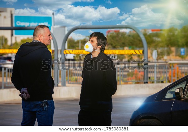 social distancing two friends\
talking in the parking lot one meter apart respecting the\
rules