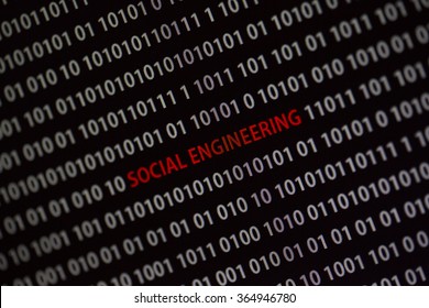 'Social engineering' text in the middle of the computer screen surrounded by numbers zero and one. Image is taken in a small angle.