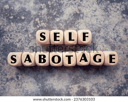 Social issue and behaviour problem concept. SELF SABOTAGE written on wooden blocks. With blurred styled background.
