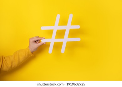 Social media concept, closeup of human hand holding and showing large big white hashtag sign