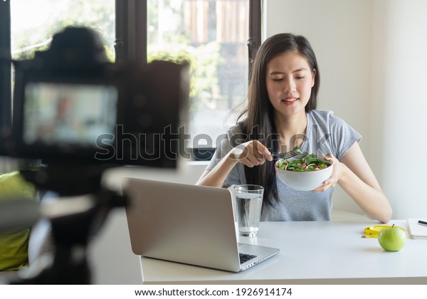 Social media and content\
creator occupation new job in future. beauty asian blogger eating\
fresh homemade salad breakfast and recording video for online\
channel live.