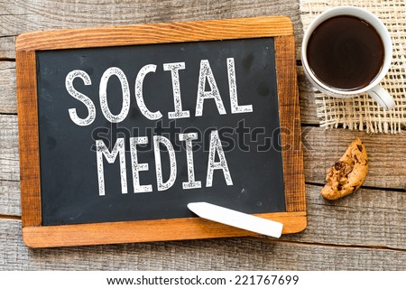 Social Media handwritten with white chalk on a blackboard, cup of coffee and biscuit on a wooden background 