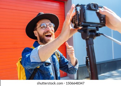 Social Media Influencer Personality Creating Content. Man Shooting Video Of Himself Using Camera On Tripod. Smiling Bearded Hipster Singer Communicating With Subscribers Outdoor Interview Concept.