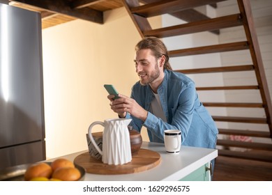 Social Media Lifestyle. A Smiling Man Updating His Status While Having A Morning Tea