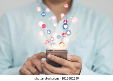 Social media and marketing concept, Businessman holding white smartphone and using colourful social media icons. - Shutterstock ID 1818882239