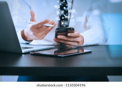 Social media and Marketing virtual icons screen concept.close up of businessman working with smart phone on wooden desk in modern office with virtual icon diagram with glass reflected view
