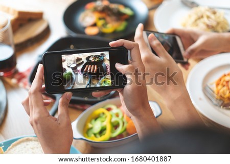 social media and modern people lifestyles. Close up hands of food blogger influencers taking picture of meal dinner post to social media app online in restaurant.
