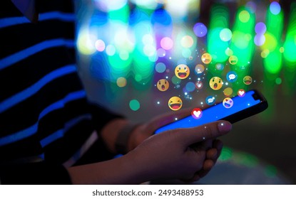 Social media technology concept. Woman using a smartphone with various colorful emoji floating above the screen, symbolizing social media interaction and digital communication. Online marketing, - Powered by Shutterstock