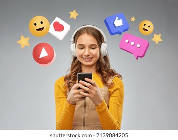 Social Media, Technology And People Concept - Smiling Teenage Girl In Headphones Listening To Music On Smartphone Over Internet Icons On Grey Background