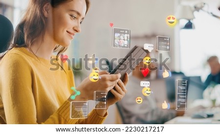 Social Media Visualization Concept: Happy Young Woman Uses Digital Tablet Computer in the Office, Social Media Posts, Smiley Faces, e-Commerce Online Shopping Digital Icons Flying Around the Device