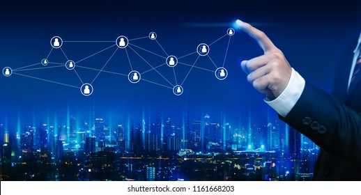 Social network connection concept, Hand of business man with technology graphic icon and future city background at night, Panorama view