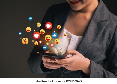 Social network emoticons pops up over the smartphones of a young business woman watching live streaming. People using social media application concept.