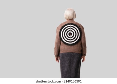 Social problems of the elderly idea. Target on the back of an old woman. The concept of the vulnerability of the old age people and people of retirement age. Background with copy space.
