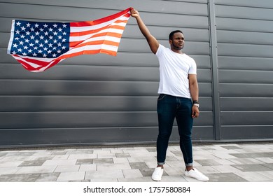 Social And Racial Equality. Young Afro American Guy In Casual Clothes Holding USA Flag While Standing On The Street