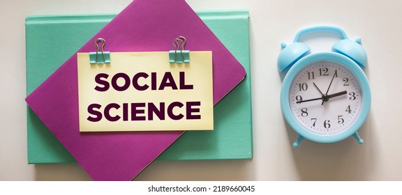 Social Science Memo Written On A Notepad, Next To A Clock On A White Background