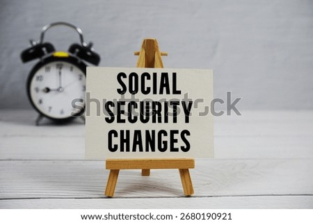 Social Security Changes text with easel and alarm clock on wooden background