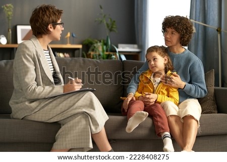 Social worker making notes while talking to adoptive parent and child during their meeting at home