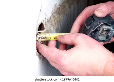 A Socket Outlet With Exposed Aluminum Wires. A Handyman With Psoriasis Measures The Wires. Wiring Repair Concept.