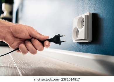 Socket, plug and electric power outlet. Man unplugging or holding cable wire cord in hand. Save energy. Electricity from home wall. Electrical current conservation. Insert adapter or charger.