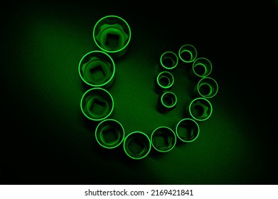 Socket Wrench Heads Made Of Chrome Vanadium On The Dark Grainy Background In A Neon Green Light. They Are Formed A Strange Symbol. Background Picture.