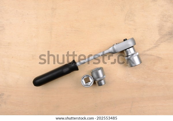 Socket wrench on wood\
background 
