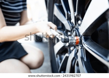 Socket wrench tool in hands of woman,closing screws the bolts,tighten the nuts or unscrews the wheel nuts,change wheel,checking the car tires before traveling,maintenance,service and repair concept