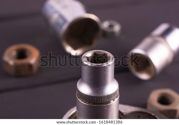 Socket wrenches\
and nuts on a dark\
background.