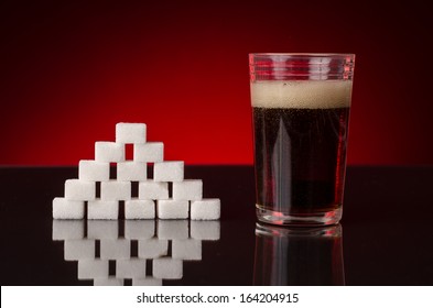 Soda With Bubbles In A Glass, Next To A Pyramid Of Sugar Cubes