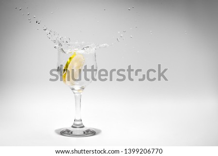 A soda drink splash photographed as a lemon slice falls into the glass.