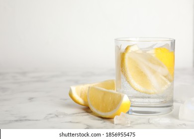 Soda Water With Lemon Slices And Ice Cubes On White Marble Table. Space For Text