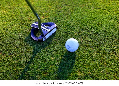 Sodertalje, Sweden - October 2021: A White Head Of A Putter On A Golf Green And A Rolling Ball Which Is Out Of Focus. Selected Focus.