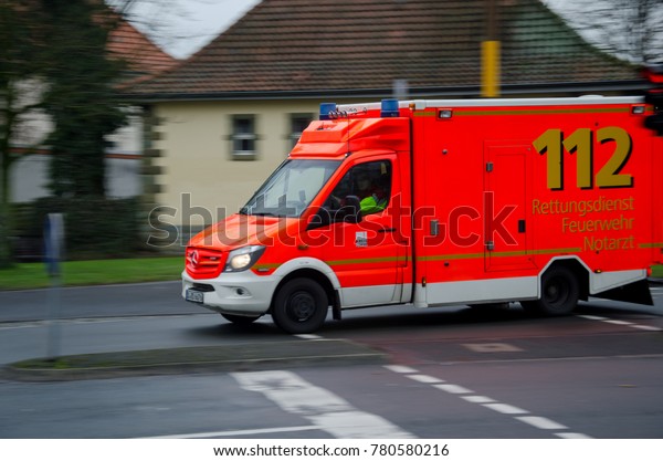Soest, Germany - December 23, 2017:  German\
ambulance service car drives on a street. 112 is the European\
emergency number that can be dialed free of charge is used for fire\
and medical emergency.