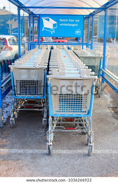 SOEST,\
NETHERLANDS - February 28, 2018. Line of supermarket carts of Ahold\
Albert Heijn Delhaize (AH) international super market chain and\
Dutch text \'take here your trolley car\'.\
