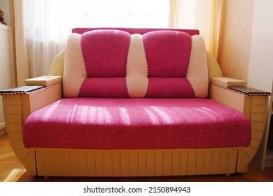 sofa bed made of pink fabric with wooden armrests. multi-colored, simple furniture for the house. sale of used items. - Shutterstock ID 2150894943