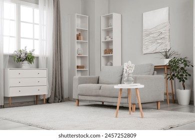 Sofa, decor on shelves, table with flowers in vase and picture on grey wall in interior of living room - Powered by Shutterstock