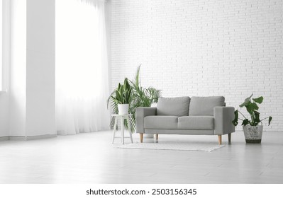 Sofa and houseplants near white brick wall in living room - Powered by Shutterstock