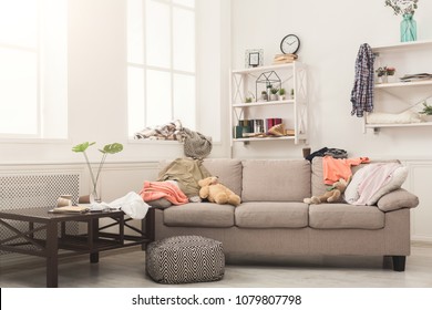 Sofa In Messy Living Room With Many Stack Of Clothes. Disorder And Mess At Home, Copy Space