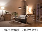 Sofa, shelving unit, houseplants and glowing lamps in interior of living room