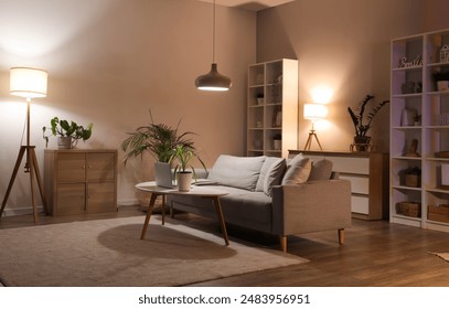 Sofa, shelving unit, houseplants and glowing lamps in interior of living room - Powered by Shutterstock