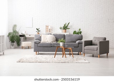 Sofa, tables and houseplants near white brick wall in interior of living room - Powered by Shutterstock