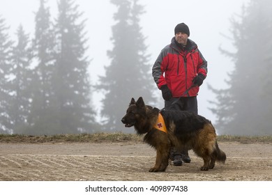 Sofia, Bulgaria - April 20, 2016: A Man And His Dog At The Search And Rescue Team At Bulgarian Red Cross Are Participating In A Training In The Foggy Mountain. 