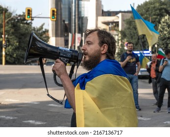 Sofia, Bulgaria, June 13, 2022: A bearded man wrapped in Ukrainian flag with a loudspeaker in his hand speaks at the meeting against the war in Ukraine opposite the Russian Embassy in Sofia, Bulgaria.