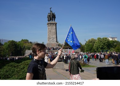 Sofia, Bulgaria - May 09, 2022: Man with Ukrainian ribbon on his hand waved the EU flag in front of a monument to the Soviet Army, where supporters of Russia celebrate Victory day at the same time