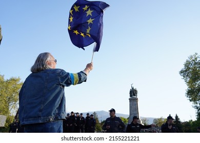 Sofia, Bulgaria - May 09, 2022: Man with Ukrainian ribbon on his hand waved the EU flag in front of a monument to the Soviet Army, where an event in defense of the Russian monument held at same time