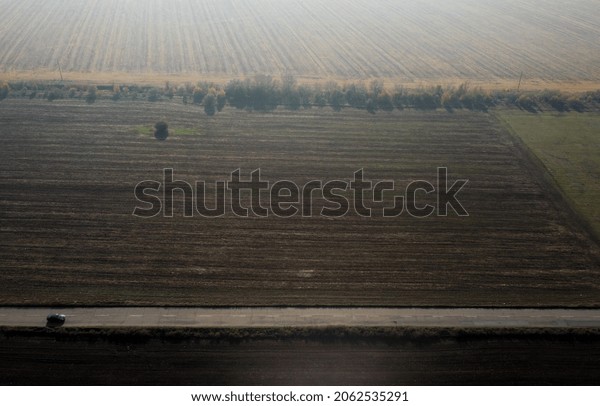 Sofia, Bulgaria October 2021. A car passes on a\
straight road between plowed agricultural land on the outskirts of\
the capital.