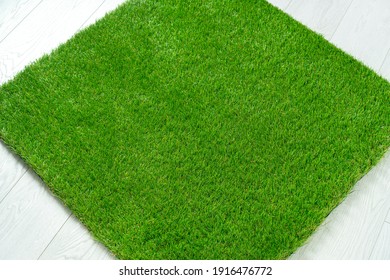 Soft artificial turf mat lying on the white wooden floor