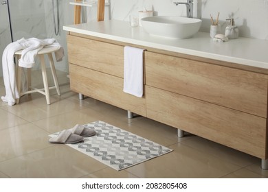 Soft Bath Mat And Slippers On Floor In Bathroom