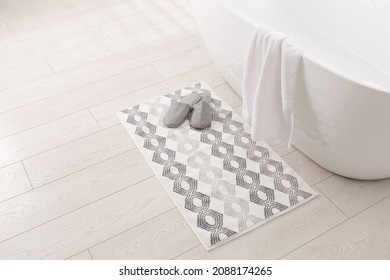 Soft Bath Mat And Slippers On Floor In Bathroom